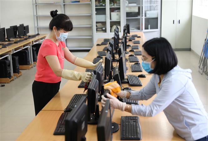  Trong ảnh: Nhân viên y tế Trường THPT Nguyễn Gia Thiều, quận Long Biên hướng dẫn giáo viên sử dụng thiết bị đo thân nhiệt đúng cách. Ảnh: Thanh Tùng - TTXVN