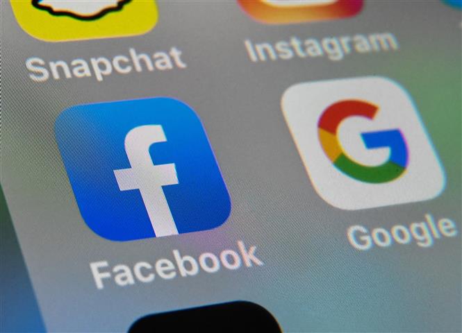 Trong ảnh: Biểu tượng của Facebook và Google trên một màn hình máy tính bảng. Ảnh: AFP/TTXVN