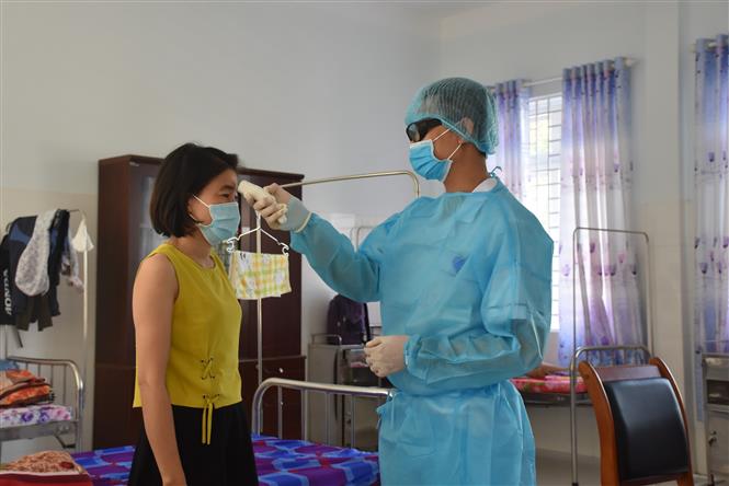 Điều dưỡng tại Khu cách ly tập trung của tỉnh Bà Rịa-Vũng Tàu kiểm tra thân nhiệt của người cách ly tập trung. Ảnh: Hoàng Nhị - TTXVN